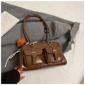 Detail of vintage brown shoulder bag with dual front pockets and fluffy bear pendant