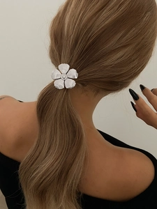 Close-up of silver metal flower hair clip with petal texture on blonde ponytail hair