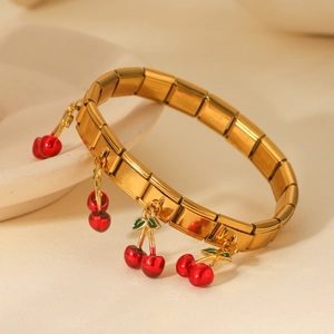 Macro shot of gold stainless steel modular bracelet with four red cherry charms detail