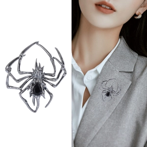 Silver spider brooch with black drop-shaped gemstone shown on a suit lapel