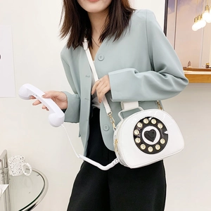 Detail of creative white patent leather phone shaped crossbody bag with vintage dial
