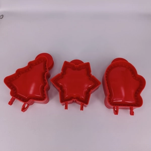 Detailed view of red plastic Christmas tree snowflake and mitten cookie cutters set