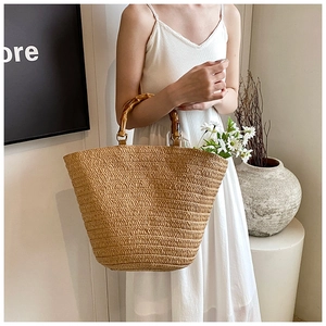 Detailed close-up of woven straw texture and natural bamboo handle on a large summer tote