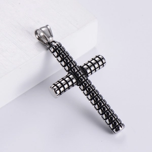 Macro shot of silver stainless steel cross pendant with textured grid industrial design