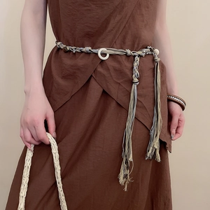 Detail of bohemian hand-woven waist chain with beads and tassels on a brown dress