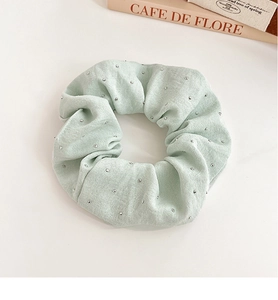 Detail of light green rhinestone scrunchie with sparkling silver studs on soft fabric