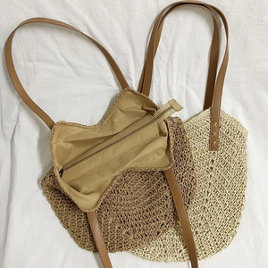 Handmade woven tote bag with leather straps in dual-tone straw design for beach vacations