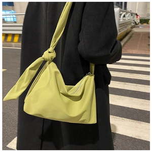 Close-up of a stylish lime green hobo bag featuring a decorative knot detail on the shoulder strap