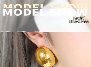 Close-up of model wearing large oval gold earrings with a polished mirror finish