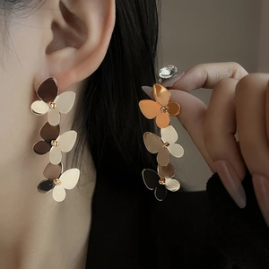 Close-up of triple layered butterfly drop earrings in gold finish on female model