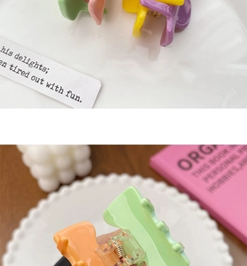 Detail of colorful candy-colored mini hair claws on a decorative white ceramic tray