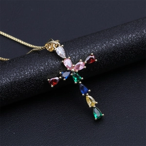 Détail d'un pendentif croix plaqué or orné de pierres en zircone cubique multicolores