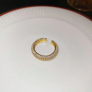 Detail of gold-plated crossover pearl ring with micro-pave white zircon inlay on ceramic plate
