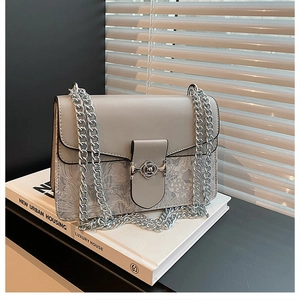 Close-up of a stylish grey chain bag featuring a delicate floral pattern and silver flower clasp