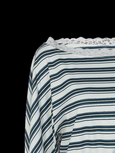 Detail of the white lace trim and multi-color stripes on the long sleeve knit top