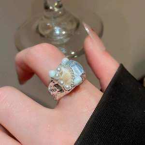 Macro shot of silver ring with sea shell, turquoise stones, and faux pearls in detail