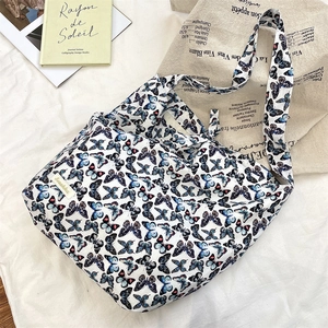 Close-up of white canvas shoulder bag featuring detailed blue butterfly print and texture