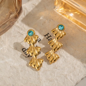 Boucles d'oreilles coquillage plaquées or 18 carats avec zircons et pierres bleues sur papier