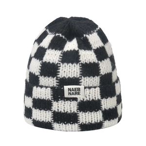 Nahaufnahme der schwarz-weißen Schachbrett-Strickmütze mit Textur und NAEB NARE Label
