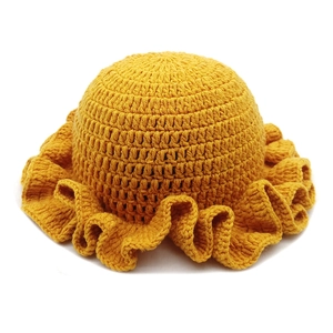Macro detail of vibrant yellow crochet knit hat with stylish ruffled brim texture