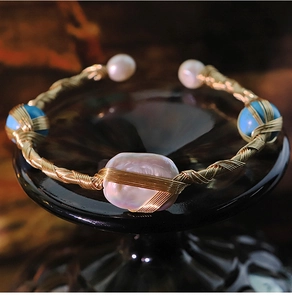 Detail of handmade gold wire bracelet featuring baroque pearl and turquoise stones