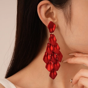 Detailed close-up of layered red petal tassel earrings worn by a fashion model