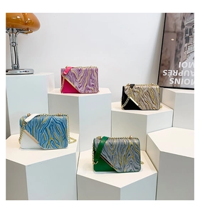 Detail showing four chain bags with textured patchwork design and metal straps on stands