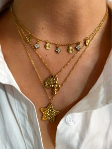 Detailed view of triple-layered gold necklaces with cross, star and coin pendants on model