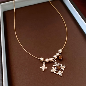 Detail of vintage gold snake chain with tiger eye stone and fleur-de-lis pendant