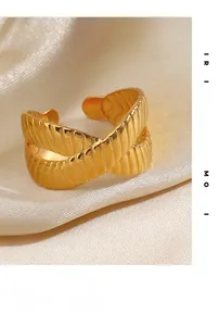 Detailed close-up of golden crossover ring with textured grooves on silk fabric