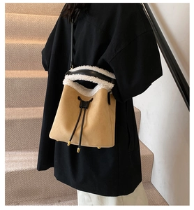 Detail of suede bucket bag with white faux fur trim and black leather drawstring closure