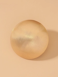 Macro view of a golden spherical earring with a sophisticated brushed metal texture finish