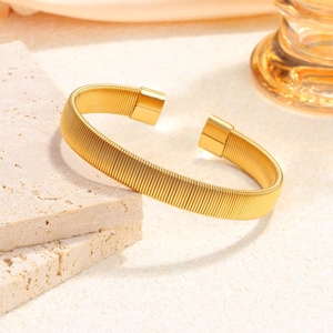 Elegant gold woven mesh wire open cuff bracelet displayed on minimalist stone
