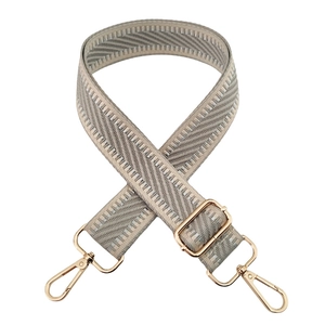 Detail of beige woven bag strap with adjustable golden metal buckle and lobster clasp