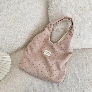Detail of floral corduroy tote bag showing delicate flower print and woven brand label