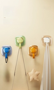Detail showing colorful adhesive wall hooks in blue, green, and orange with gold accents