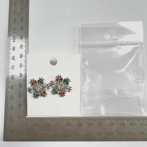 Macro view of Christmas snowflake earrings with rhinestones next to a measuring ruler