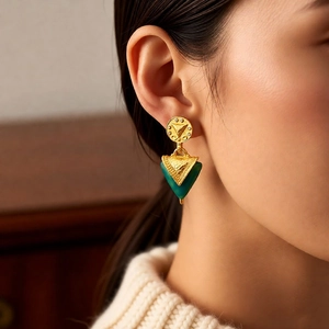 Nahaufnahme von Vintage-Dreieck-Ohrringen in Gold, getragen von einem Modell