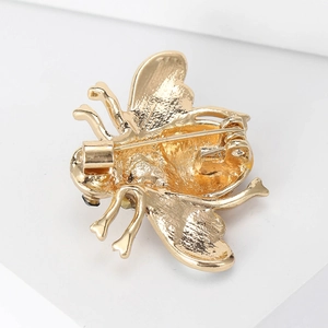 Close-up of the golden bee brooch back showing the pin mechanism and metal texture
