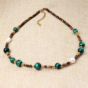 Tiger eye and green agate beaded necklace with pearls and gold accents on woven fabric