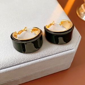 Close-up of C-shaped resin hoop earrings with black finish and gold plated inner detail