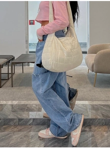Modella indossa una borsa hobo bianca trapuntata a nuvola in un interno moderno