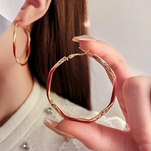 Modern twisted gold hoop earrings with red enamel coating for a stylish retro aesthetic