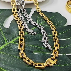 Detail of square link chain necklaces in gold and silver finish on green monstera leaves
