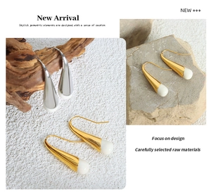 Close-up of geometric cone earrings with gold plating and white enamel inlay details