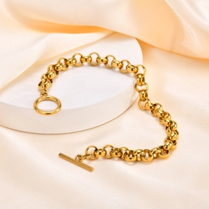 Detail shot of golden OT buckle bracelet on white stand with elegant beige silk