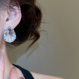 Detailed view of teardrop crystal stud earrings with silver-tone four-prong setting on model