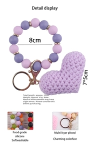 Detail of purple silicone beaded wristlet keychain with hand-knitted heart and golden clasp