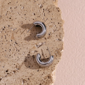Close-up of polished silver double-layered C-shaped earrings on natural stone