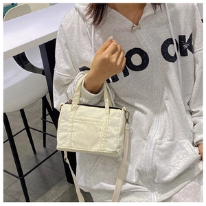 Detail of white corduroy mini Boston bag with front pocket and detachable shoulder strap